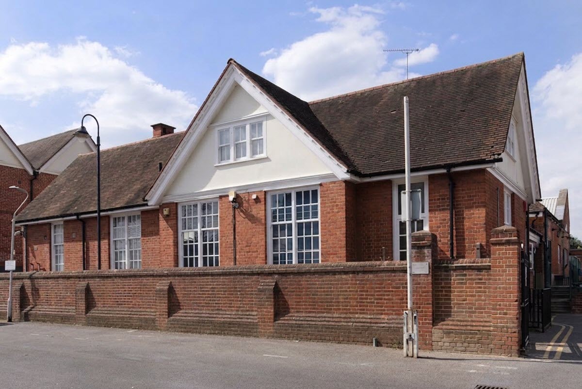 Exterior view of the Family Research Centre building, featuring red brick walls, large white-framed windows, and a prominent gable, set behind a low brick boundary wall.