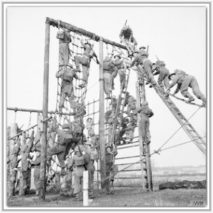 Soldiers in full military uniform scale tall cargo nets and wooden ladders during an outdoor obstacle course training exercise.